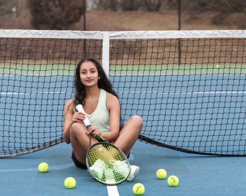 a woman sitting on a tennis court holding a racquet